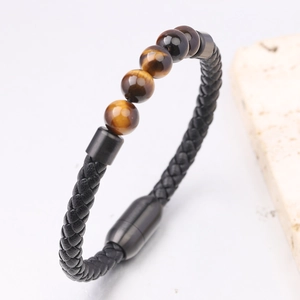 Dettaglio di pietre occhio di tigre su bracciale in pelle intrecciata nera con chiusura magnetica