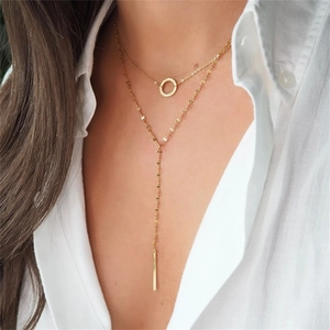 Close-up of double-layer gold necklace featuring a round charm and geometric bar pendant