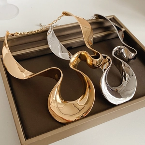 Detailed macro view of gold and silver irregular geometric wave pendant necklaces