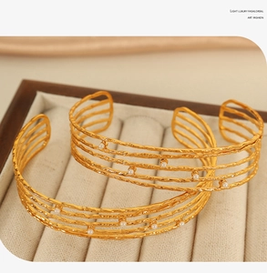 Detail of 18K gold C-shaped cuff bracelet with layered wire and pearl accents in a box