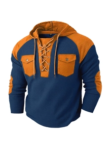 Detailed close-up of blue and orange knitted hoodie with drawstring and chest pockets