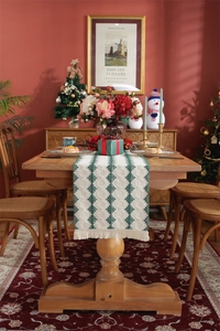 Detail of green and beige woven table runner with diamond patterns and tassels