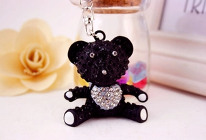 Nahaufnahme eines schwarzen Strass-Teddybären mit einem silbernen Herz als Anhänger