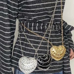 Three mini heart-shaped rhinestone crossbody bags in gold silver and black shown on model