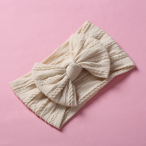 Detailed view of beige cable knit pattern on infant nylon headband with knotted bow