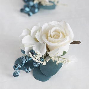 Groom boutonniere with white rose, blue berries and green leaves for weddings and banquets