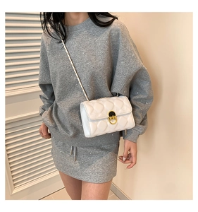 Detail of white quilted leather crossbody bag with elegant gold metal lock on front