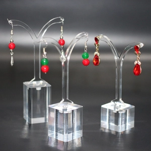 Macro detail of acrylic earring display stands featuring elegant red and green bead pendants