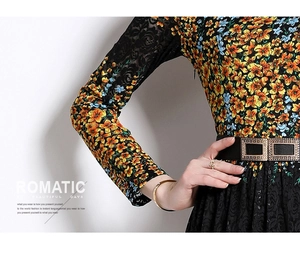 Vista de detalle de estampados florales naranjas en vestido de encaje negro con cinturón