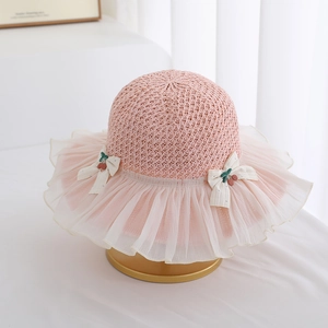 Detail of pink straw hat with white chiffon brim and cherry bow accents for kids