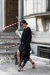 Detail of elegant black knitted top and tiered ruffle chiffon skirt in outdoor street style