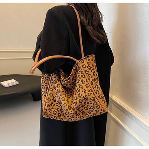Detail of leopard print tote bag with brown straps styled on a black wool coat