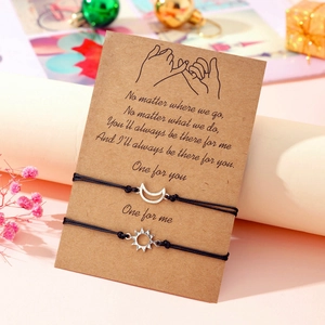 Detail of sun and moon alloy charms on black woven cords with a sentimental card