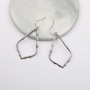 Detail view of silver water drop earrings with irregular geometric textured finish