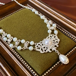 Détail du collier de perles baroques avec motif floral en cristal et pendentif goutte