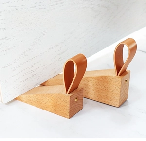 Detail view of beech wood door stopper with brown leather loop and metal rivet