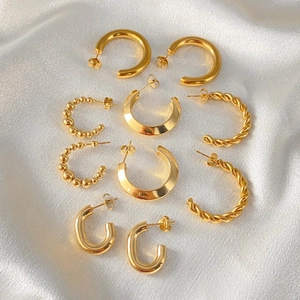 Close-up of gold-plated stainless steel C-shaped hoop earrings with twisted and beaded designs