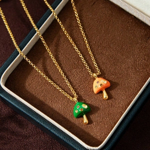 Macro detail of enamel mushroom pendant necklace with colorful zircon stones in gold finish