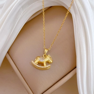 Detail of a gold rocking horse pendant with white zircon on elegant white silk