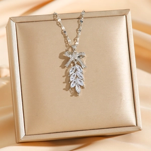 Elegant silver zircon leaf bow necklace displayed on premium champagne satin background
