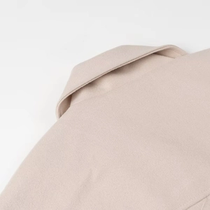 Detail shot showing the lapel collar and wool blend texture of the beige short coat