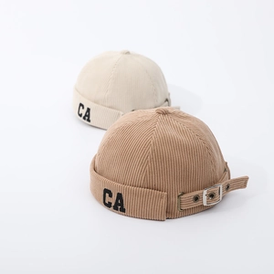 Detail view of corduroy docker caps in khaki and beige with CA embroidery and metal buckle
