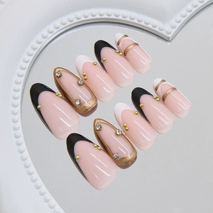 French almond press-on nails with black borders, gold leaf accents and sparkling crystals