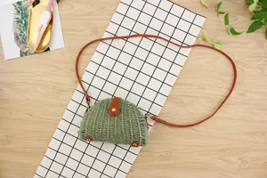 Detail view of woven straw crossbody bag in green raffia with brown leather straps