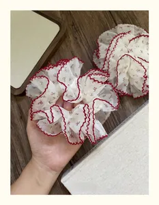 Détail de chouchous en tulle floral avec bordure en dentelle rouge et fleurs