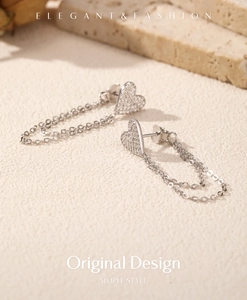 Macro shot of silver S925 heart tassel earrings with sparkling crystals on beige stone