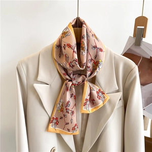 Floral print long silk scarf styled on a white blazer lapel with elegant warm tones