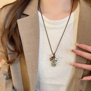 Detailed view of an ethnic necklace with stone beads and rectangular pendant on brown cord