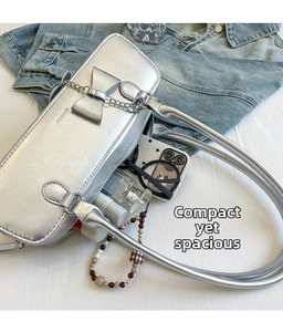 Close-up of silver shoulder bag showing spacious interior with sunglasses and perfume