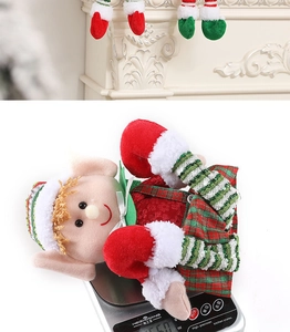 Detail of Christmas elf doll in red and green plaid skirt being weighed on a scale