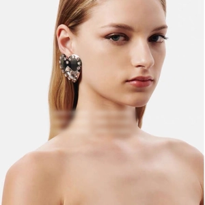 Chunky silver heart earrings with full white rhinestone inlay worn by a model
