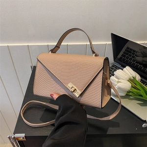 Detail of pink faux-croc skin texture and golden metal lock on a stylish handbag
