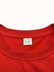 Gros plan du col du T-shirt rouge montrant la taille M et l'étiquette de matière
