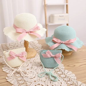 Détail de l'ensemble chapeau de paille et sac avec nœuds roses sur nappe en dentelle