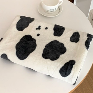 Close-up of soft coral fleece towel with classic black and white cow print pattern