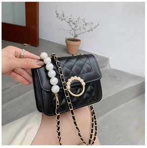 Close-up of quilted chain bag with large pearl strap and circular pearl clasp details