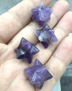 Detailed view of four Merkaba star-shaped natural purple amethyst crystals on a hand palm