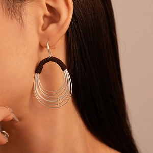 Detail of layered silver circular earrings with dark brown fabric thread wrap on model