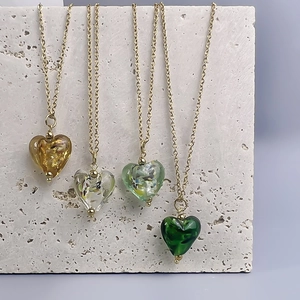 Vintage French glass heart pendant necklace in amber and green on stone background