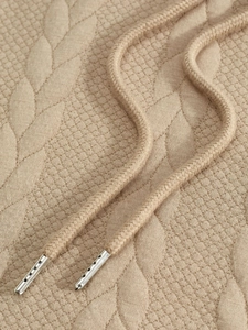 Detailed macro view of beige jacquard knit fabric and drawstring with silver metal tips