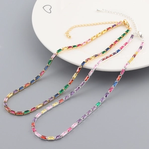 Gold and silver rainbow zircon necklaces displayed on a decorative ceramic heart plate