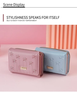 Detail of pink and blue short wallets with floral embroidery and gold brand plaque