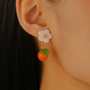 Detailed close-up of sweet fruit drop earring featuring white flower and orange bead