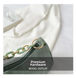 Detail view of green corduroy shoulder bag with mint green and gold metal chain strap