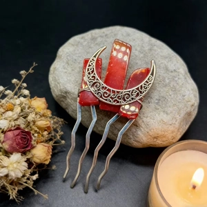 Macro detail of silver moon hair comb with red crystals and gold foil inclusions