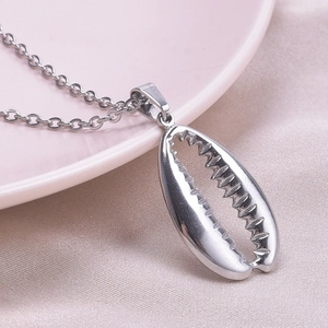 Detailed close-up of a silver shell pendant necklace on a soft silk background